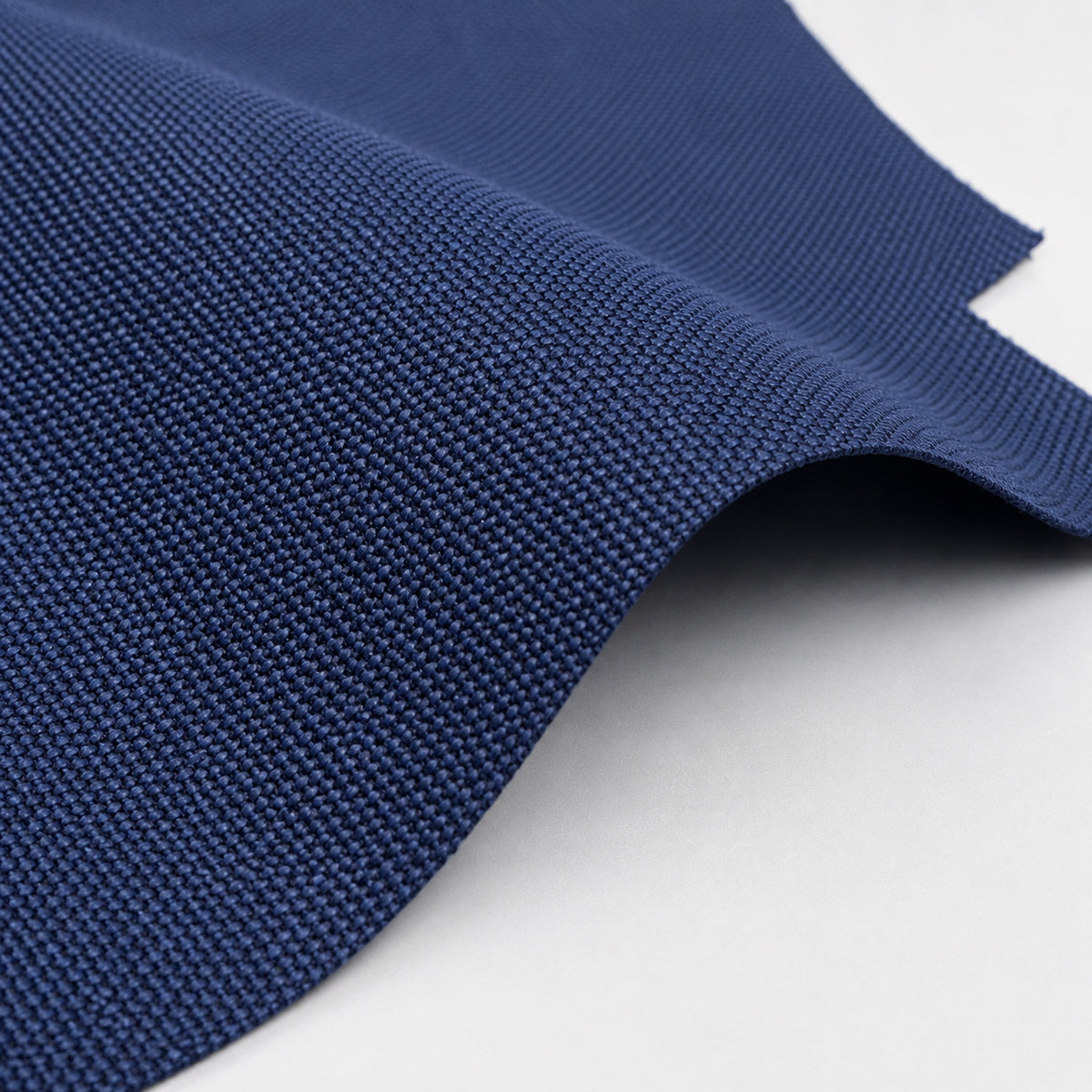 A close-up of a textured navy blue woven fabric, shown draped with a clean fold on a plain white background.