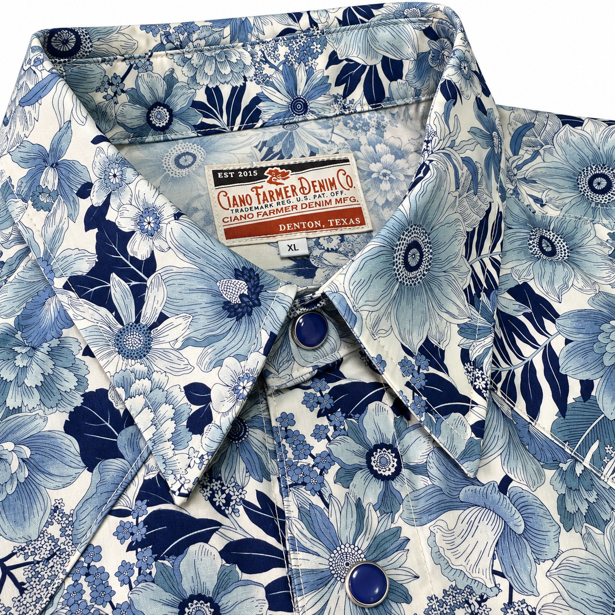 A close-up of a men's button-down shirt by Ciano Farmer Denim Co., featuring a blue and navy floral print on a white base.